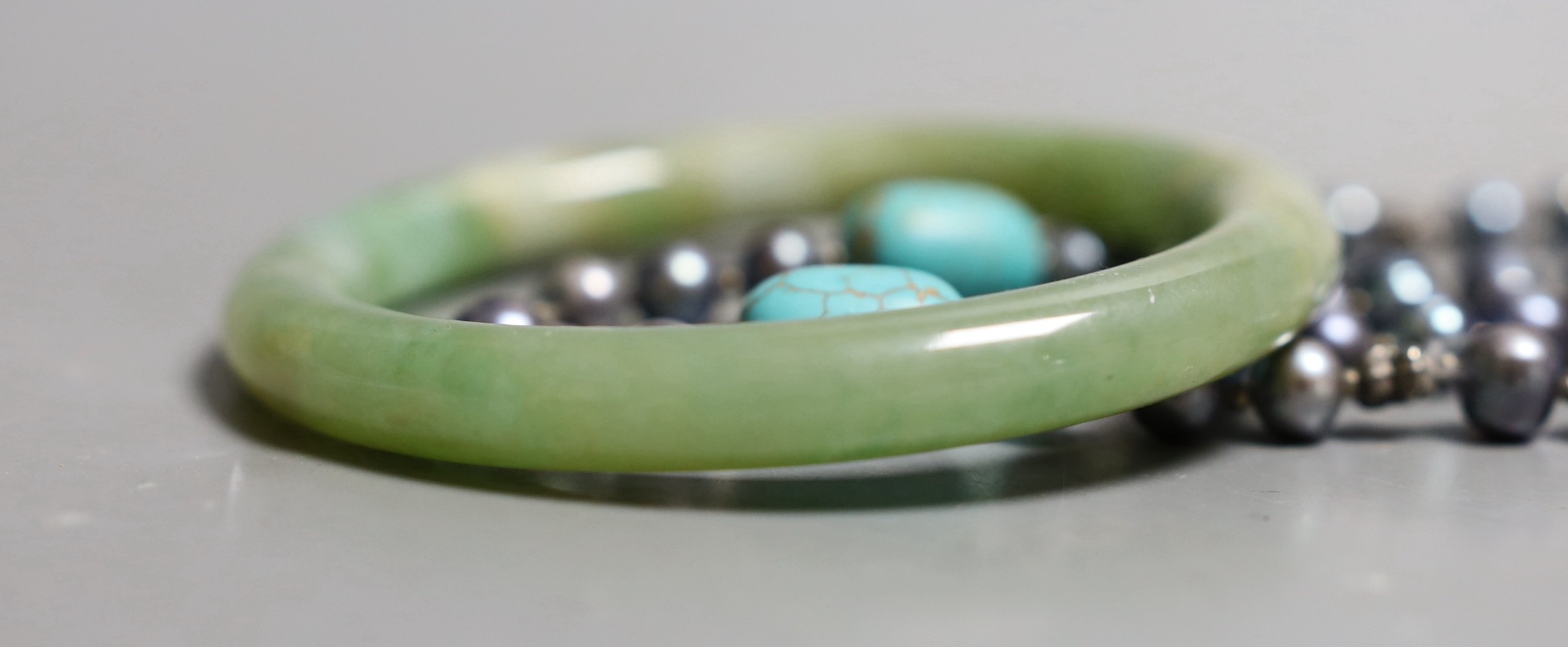 A white metal and paste set bow brooch, a green hardstone bangle and a Tahitian cultured pearl and turquoise set necklace.